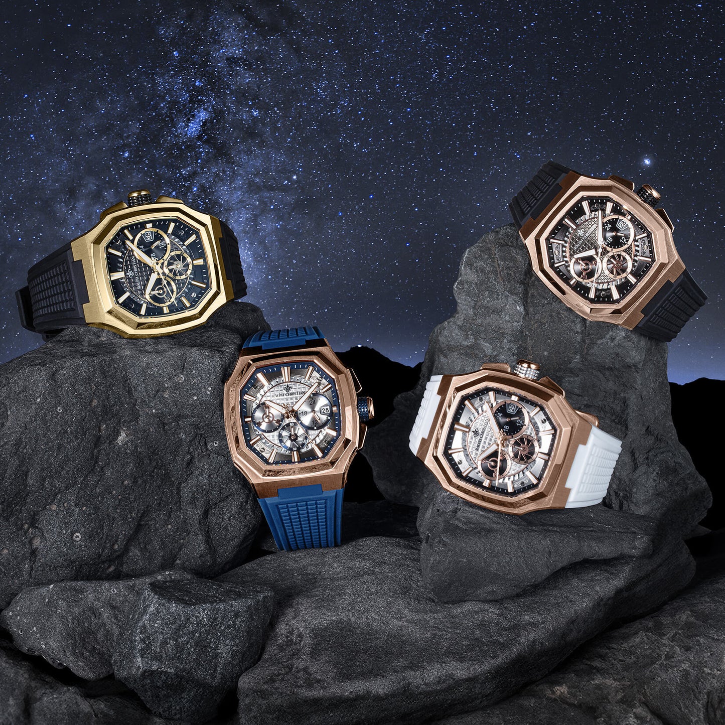 Four ornate watches on rocks with a starry night sky background
