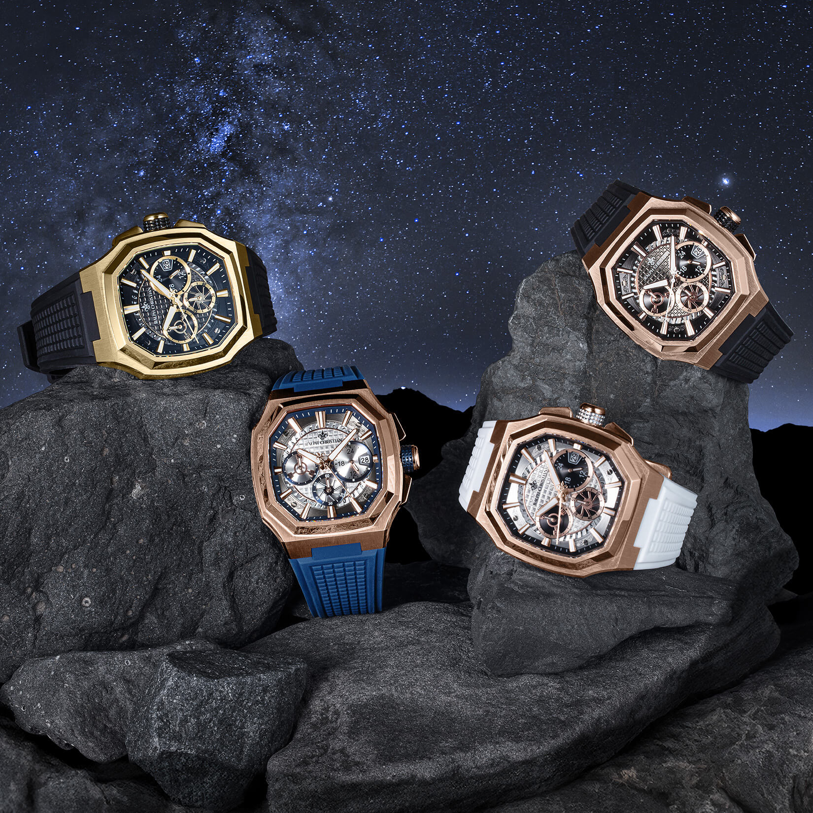 Four ornate watches on rocks with a starry night sky background